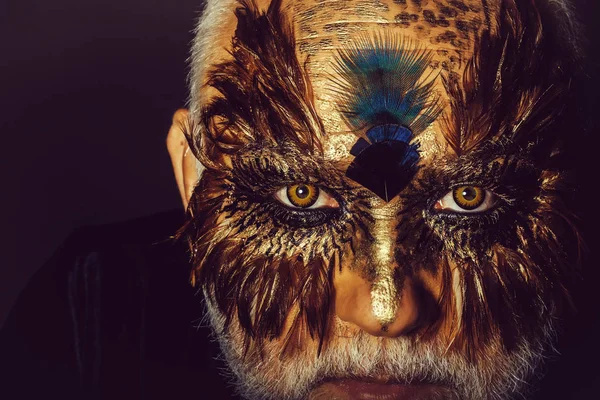 old man in feather mask