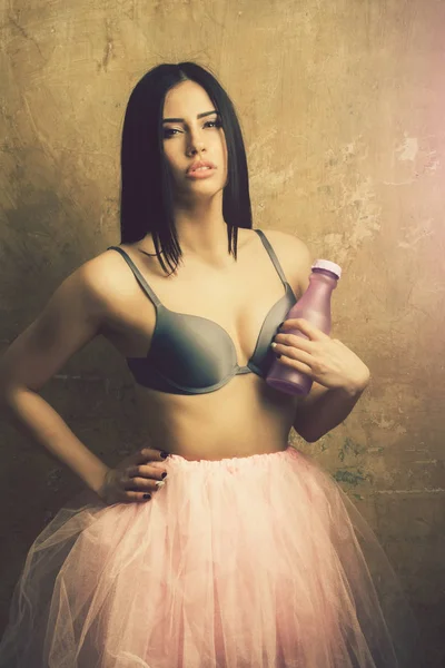 Jolie femme sexy en jupe rose et soutien-gorge avec bouteille — Photo