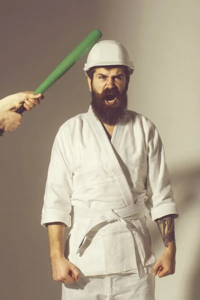 Bearded shouting karate man in kimono, helmet with baseball bat — Stock Photo, Image