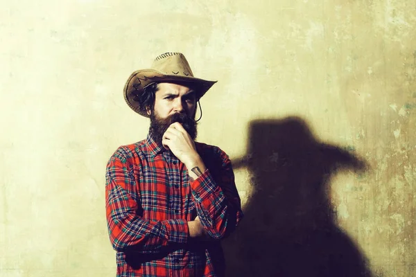Uomo barbuto in cappello da cowboy e ombra nera sul muro — Foto Stock