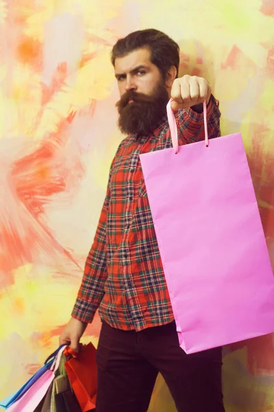 Ernstige bebaarde man met kleurrijke papieren draagtassen — Stockfoto
