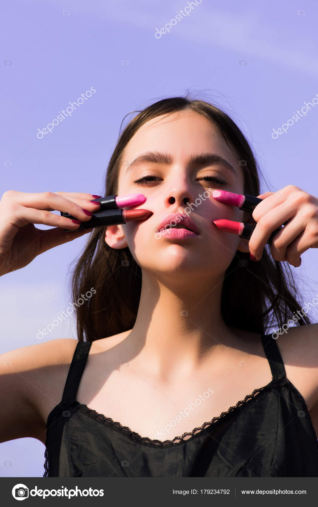 Girl posing with pink lips and lipsticks on blue sky Stock Photo by 179234792