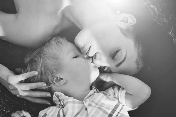 Sorrindo menino bonito e mãe bonita deitado na grama verde — Fotografia de Stock