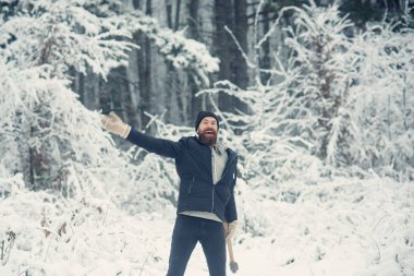 Sakallı adam karlı ormanda balta ile.