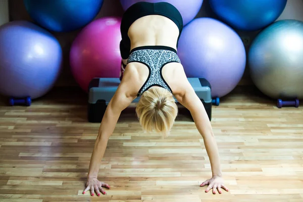 Flicka idrottsman göra handstående med ben på stepper i gymmet — Stockfoto