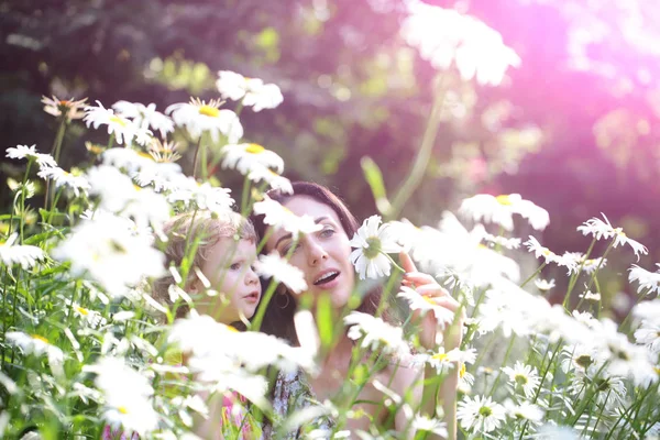 Mother and daughter on field with blossoming daisy flowers