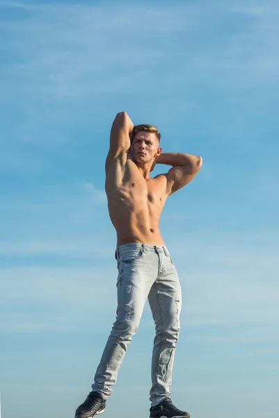 Sportsman show strong body in jeans on blue sky — Stock Photo, Image