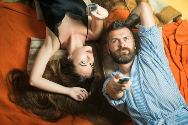 Homme barbu et femme aux cheveux longs tiennent la télécommande . — Photo