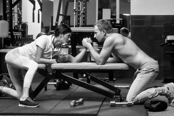 Braccio di ferro muscolare uomo e ragazza in palestra — Foto Stock