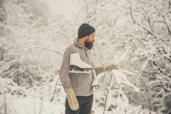 Homem barbudo segurar patins na floresta de inverno nevado, natal — Fotografia de Stock