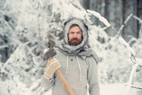 Homem barbudo lenhador segurar machado na floresta de inverno nevado, camping — Fotografia de Stock