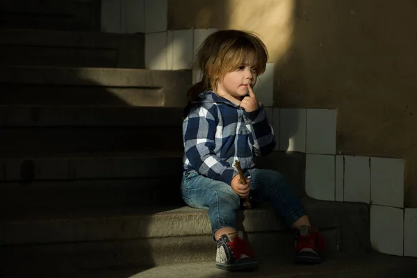 Jongen met denken gezicht zitten op de trappen van het huis — Stockfoto