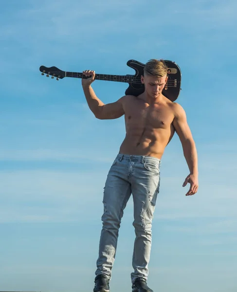 Hombre con torso muscular sostener la guitarra eléctrica en el cielo azul —  Fotos de Stock