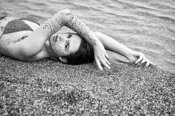 Pretty girl lies in yellow swimsuit top on sea beach — Stock Photo, Image