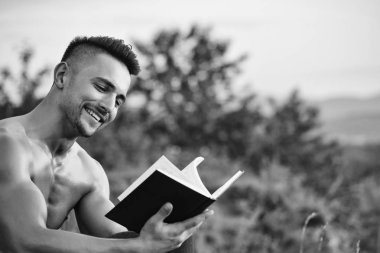Kaslı seksi vücut ve çıplak göğüs kitap açık güneşli gün ile oturan genç gülümseyen yakışıklı