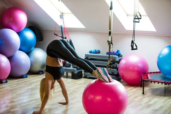 Kvinna idrottsman göra handstående med ben på fit boll — Stockfoto