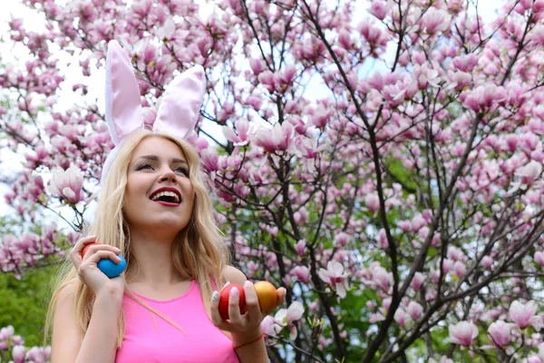 Szczęśliwa dziewczyna w uszy królika, śmiejąc się z kolorowymi jajkami — Zdjęcie stockowe