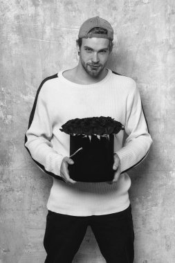 Sakallı gülümseyen adam kırmızı gül kutusu dokulu duvar tutar