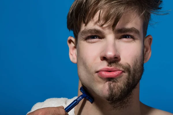 Bachelor shave half bearded face with razor on blue background — Stock Photo, Image