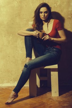 Kahverengi cups ile beyaz ahşap sandalye üzerinde oturan güzel kız