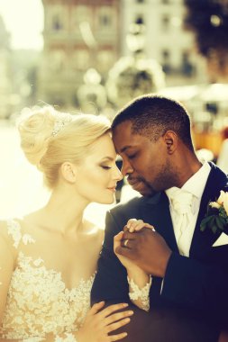 Birkaç güzel kız ya da beyaz seksi gelinlik ve yakışıklı bir adam ya da Afro-Amerikan damat güzel sarışın saçlı sevimli gelin açık havada güneşli günde üzerinde sevgi dolu şehir sokak arka plan bulanık