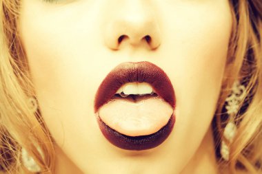 Seksi dudakları, mor ruju ve dili olan bir kadın.