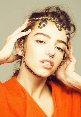 Güzel kız veya güzel bir kadın, genç, tatlı, seksi, moda model metalik gri arka plan üzerinde turuncu montlu yüzündeki kafatasları zincirle ile kıvırcık saç ve burun halkası pozlar ile