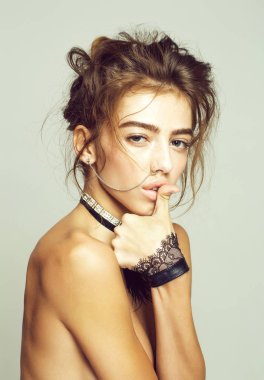 Güzel kız veya güzel bir kadın, genç, tatlı, seksi, moda model kıvırcık saçlı, Hızma ve kelepçeleri pozlar dilinde gri arka plan üzerinde başparmak ile üstsüz İncili kolye