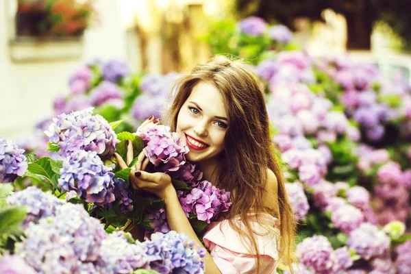 Bonita chica sonriente en hortensias flores —  Fotos de Stock