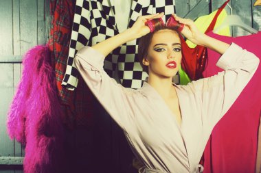 Sabahlık saç-Silindirler ile bir güzel genç seksi ev hanımı kadın portre görünümünü dolap birçok parlak elbise kaldırdı elleriyle, yatay resim arasında ayakta kafasına