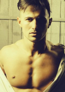 Seksi ciddi şehvetli kas genç maço adam ahşap arka plan üzerinde dikey resim kapalı duran Beyaz gömlekli çıplak gövde ile