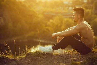 kaslı seksi vücut ve çıplak göğüs açık zemin güneşli günde oturan genç maço erkek modeli atlet