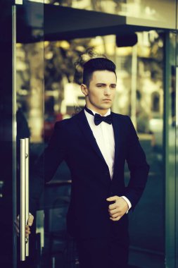 Genç adam takım elbise giyip kendine güvenerek papyon takıyor. Kendinden emin iş adamı..