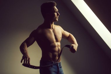 Seksi genç adam kas vücut ve deri kemer tutarak pencere poz çıplak gövde