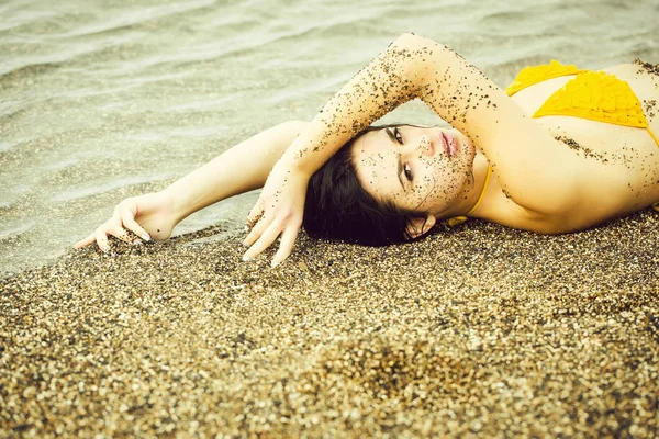 Linda chica se encuentra en traje de baño amarillo superior en la playa de mar —  Fotos de Stock