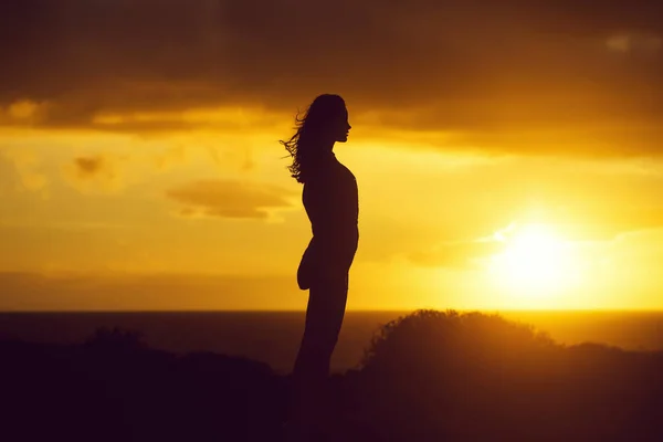 Black silhouette of pretty girl on sea beach at sunset