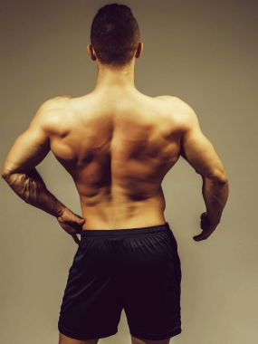 genç yakışıklı maço adam vücut geliştirmeci seksi kaslı atletik vücut çıplak gövde ve gri arka plan üzerinde Studio güçlü sırt ile
