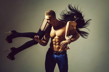 kot pantolon ile seksi kaslı atletik vücut yakışıklı maço erkek genç çift altı paketi ile güçlü göbek var ya da çıplak gövde üzerinde abs siyah ayakkabı ve çorap uzun esmer saçlı kız gri tutar.