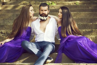 çiçeklerle karahindiba sakal taşlı merdiven güneşli açık mor elbise iki genç güzel kadınlarla Beyaz tişörtlü yakışıklı adam