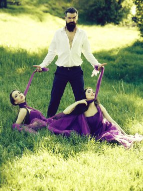 Yeşil çim güneşli açık mor elbise iki genç güzel kadınlarla yakışıklı Beyaz gömlekli sakallı