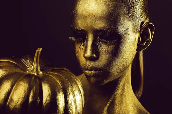 Mulher dourada com abóbora halloween — Fotografia de Stock