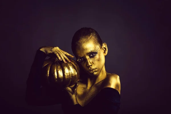 Mujer dorada con calabaza de halloween —  Fotos de Stock