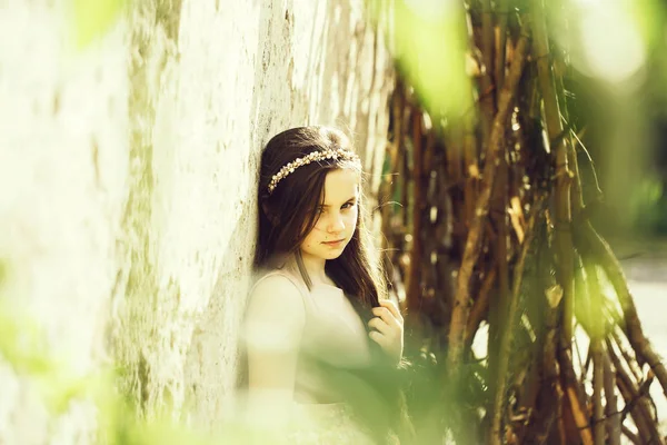 Yaprakları beyaz duvarının yakınında güzel kız — Stok fotoğraf