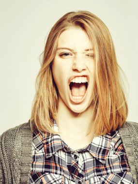 Kızgın güzel kız veya ekose gömlek ve örme ceket sarı saçlı sevimli güzel kadın genç kadın modeli palyaçoluk ve dişleri gri arka plan üzerinde gösterir