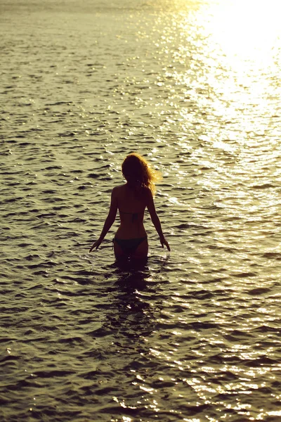 自然の背景に夕方や黄昏サンセット夏の日の海や海の水のビーチ水泳の若い女性のシルエット — ストック写真