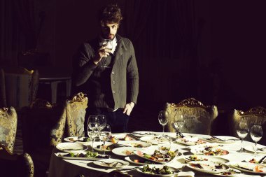 Sakal ve sarışın saçlı yakışıklı genç adam artık yemek veya artıkları ile tablo üzerinde cam Şarap içer Ziyafet yemekten sonra kirli tabak koyu arka plan üzerinde restoranda yemek