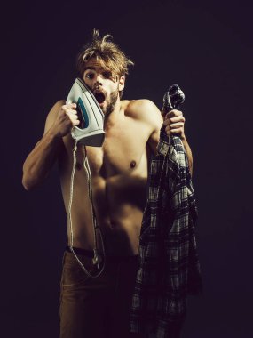 Dağınık saçlı yakışıklı üstsüz seksi adam ile beyaz demir yüzüne bağırır. Diğer elinde o koyu arka plan üzerinde ekose gömlek vardır