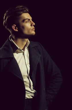 Yakışıklı adam veya genç beyaz maço, moda modeli, şık saç kesimi, saç, beyaz gömlek ve karanlık kat, klasik giyim, elleri ceplerinde siyah arka plan üzerine poz ile