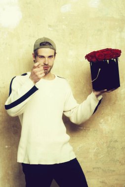 Sakallı gülümseyen adam kırmızı gül kutusu dokulu duvar tutar