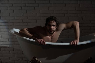 Küvet içinde oturan ıslak saçlı çocuk.